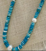 Necklace with blue beads and silver chain on a textured fabric background